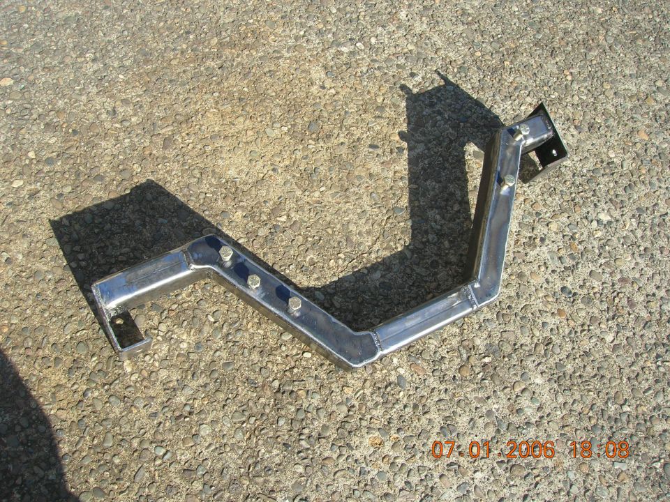 Fabricated metal Z-shaped bracket with bolts lying on gravel