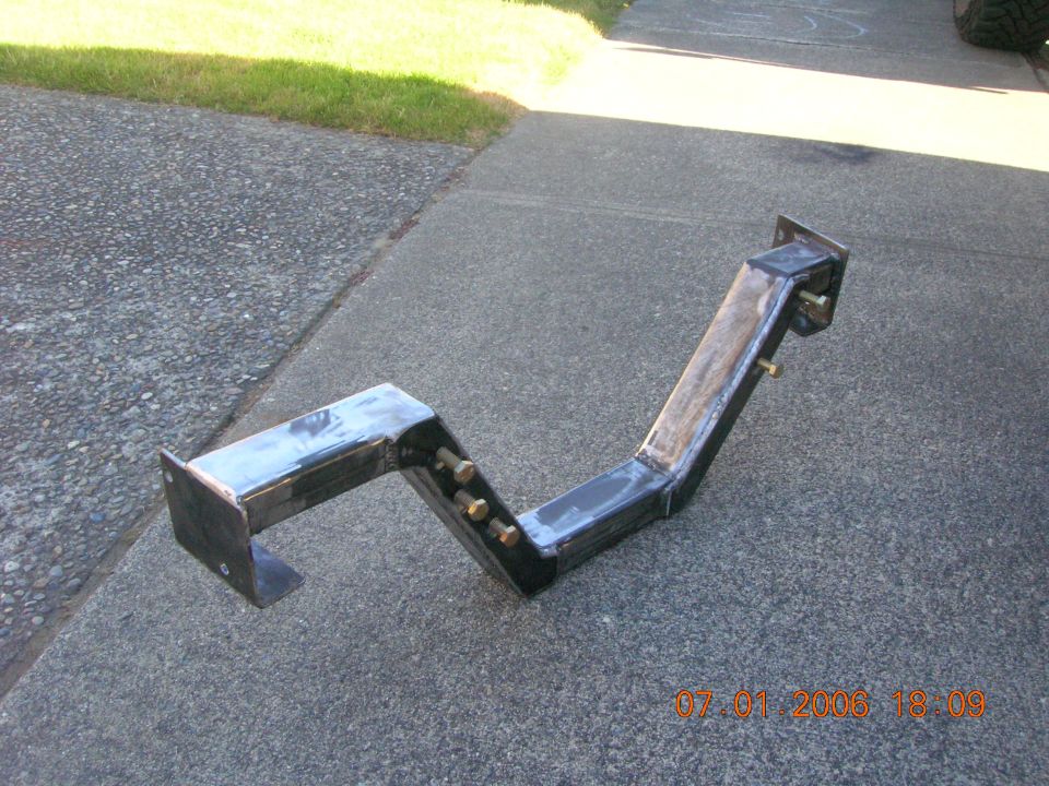 Custom black welded steel bracket with mounting plates on concrete driveway