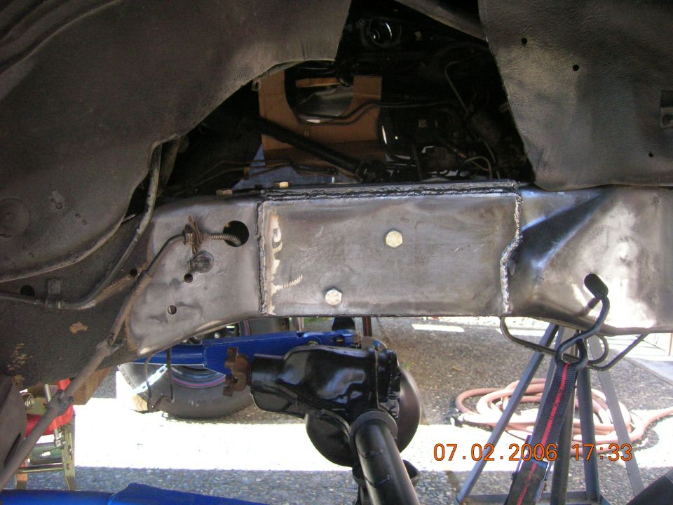 Undercarriage showing bare metal welded crossmember repair with fresh welds and bolts