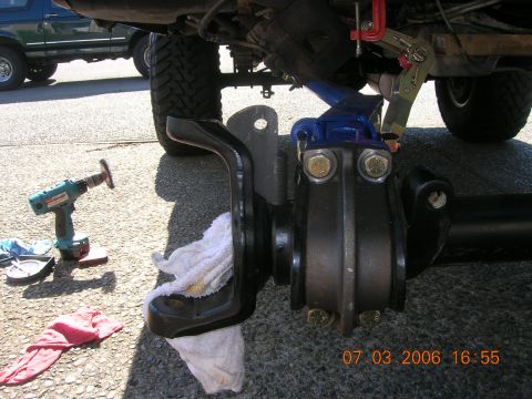 1996 Ford Bronco - Working on vehicle suspension components with tools nearby; another vehicle is parked in the background.