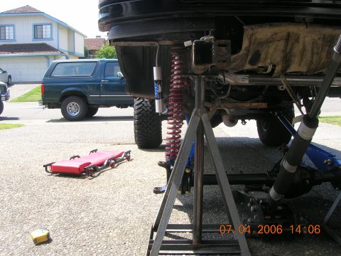 1996 Ford Bronco - A dark green Ford Bronco is shown with its suspension elevated on jack stands.