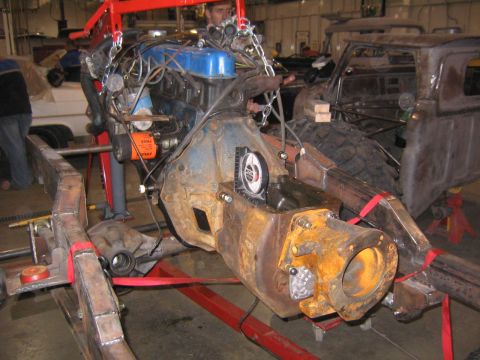 1982 Ford Bronco - Engine and drivetrain components are being worked on, with a partial view of a truck body in the background.