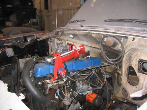1982 Ford Bronco - The engine bay of a 1982 Ford Bronco shows blue valve covers and a red engine hoist tool, suggesting drivetrain work.