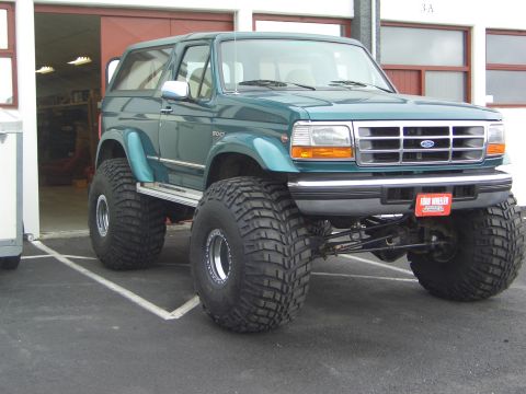1996 Ford Bronco - Modified 1996 Ford Bronco with massive tires and lifted suspension parked outdoors.