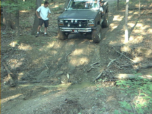 Dark pickup truck on a muddy incline, front view
