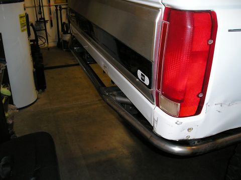 1993 Ford Bronco - Custom metal tubing replaces the rear bumper on a white SUV, with a "Pull" sticker visible near the taillight.