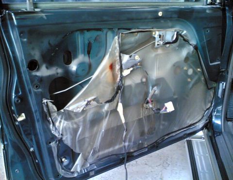 2000 Mitsubishi Montero - Interior of a car door with the panel removed, revealing the internal components and wiring harness.