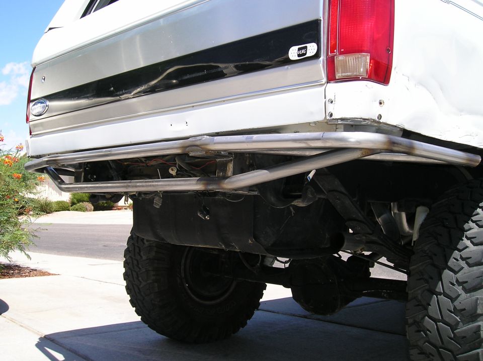 Rear underside of a white lifted Ford Bronco with tubular bumper and mud tires
