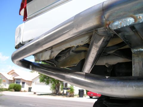 1993 Ford Bronco - Custom rear bumper on a white vehicle, showing welded metal tubing and suspension parts.