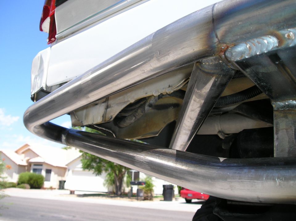 Custom welded tubular steel rear bumper on white Bronco, low angle.