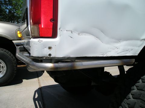 1993 Ford Bronco - The rear of a white SUV shows significant body damage and a custom metal bumper.