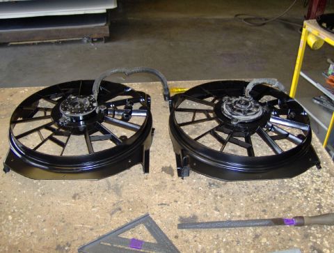 1978 Ford Bronco - Two black electric cooling fans with wiring harnesses are displayed on a workbench, alongside tools.