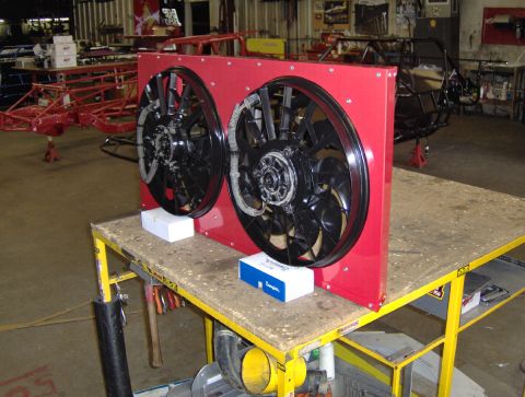 1978 Ford Bronco - A pair of electric cooling fans are displayed on a workbench in a workshop setting.