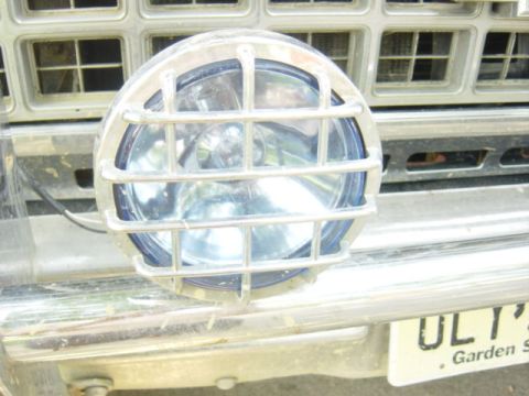 1987 Suzuki Samurai - Off-road light with chrome grille mounted on a vehicle's front end.