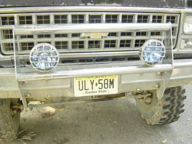 Front of a truck with a chrome grille, brush guard, and two round lights. New Jersey plate ULY-58M is visible