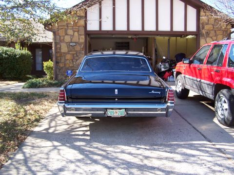 1966 Mercury Monterey - A black 1967 Mercury Monterey sedan is parked in front of a garage, with a red SUV to its right.
