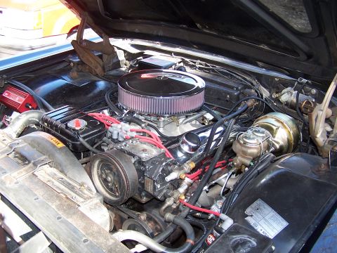1966 Mercury Monterey - Engine bay of a 1966 Mercury Monterey, a V8 engine with aftermarket air cleaner and red spark plug wires.