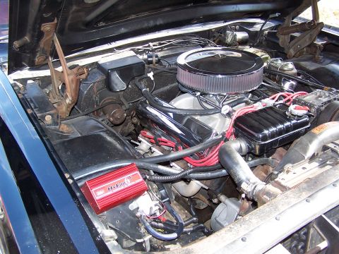 1966 Mercury Monterey - The engine bay of a classic car features a chrome air cleaner and red ignition box.