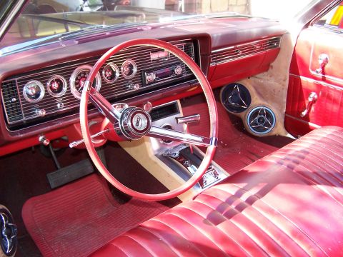 1966 Mercury Monterey - The interior of a 1966 Mercury Monterey features a red steering wheel, dashboard, and seats, with custom speaker pods.