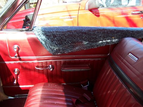 1966 Mercury Monterey - Interior view of a 1966 Mercury Monterey with a damaged window, showing the red door panel and seat.