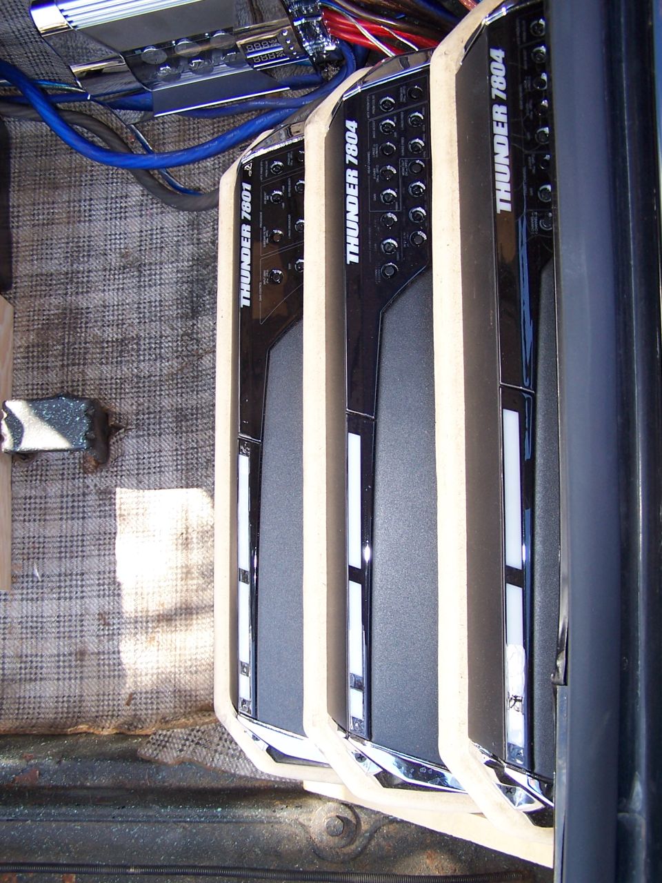 Three MTX Thunder 7801 and 7804 car amplifiers mounted on carpeted board with blue power wiring