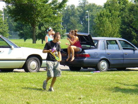 1991 Ford Probe - A blue sedan is parked with its trunk open, while people gather around it on a sunny day.