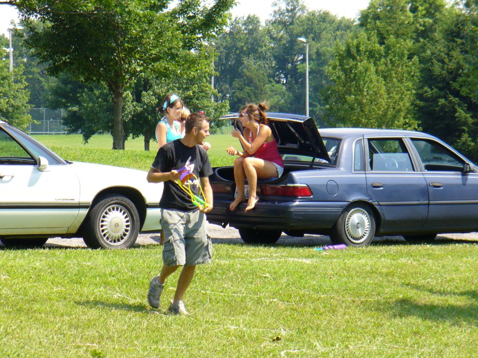 Blue sedan's rear view with open trunk, people sitting inside