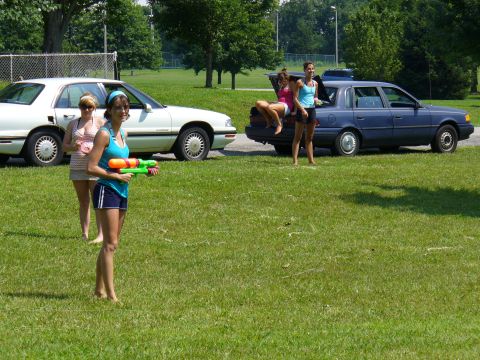 1991 Ford Probe - Two sedans are parked on a grassy area while three women stand nearby.