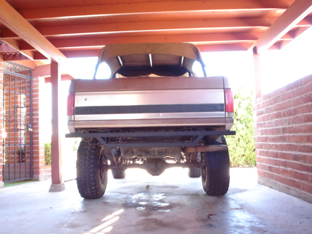 Brown 1987 Ford Bronco rear view, lifted with aftermarket bumper and soft top