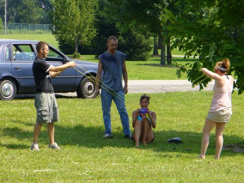 1991 Ford Probe - People gathered outdoors with slingshots near a blue sedan.