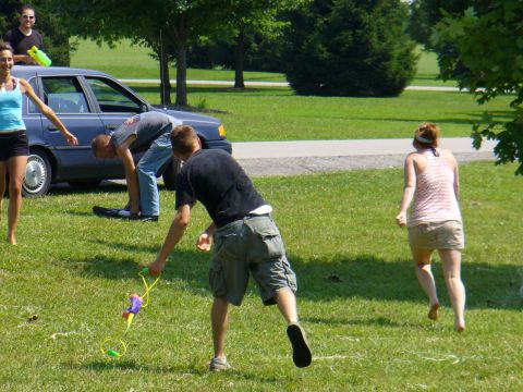 1991 Ford Probe - A group of people are enjoying a sunny day with water guns, with a blue sedan parked nearby.