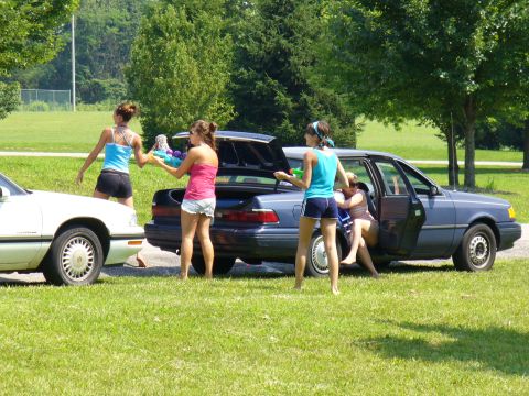1991 Ford Probe - People gathered around cars in a grassy area, possibly preparing for a water fight.