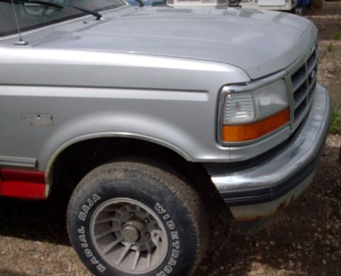 1990 Ford Bronco - Close-up of the front corner of a silver Ford F-Series truck, showing the headlight and fender detail.