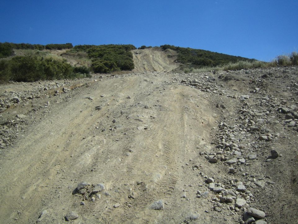 Steep rocky dirt off-road hill climb under a clear blue sky