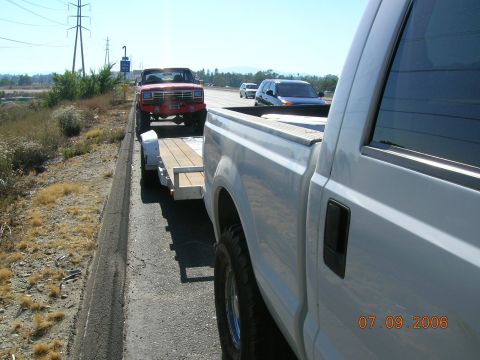 1985 Ford Bronco - Red pickup truck on trailer, towed by white pickup. Date stamp: 07.09.2006.