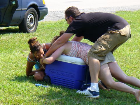 1991 Ford Probe - Three people are on the ground around a blue cooler, with a blue car in the background.