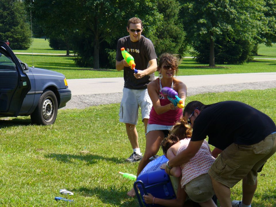 People with water guns in a park, one person is on the ground