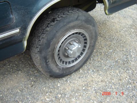 1993 Ford Bronco - A close-up view of the rear wheel and fender of a Ford truck, showing the tire and hubcap.