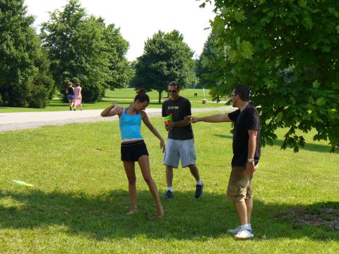 1991 Ford Probe - Three people are engaged in a water gun fight on a sunny day in a park.