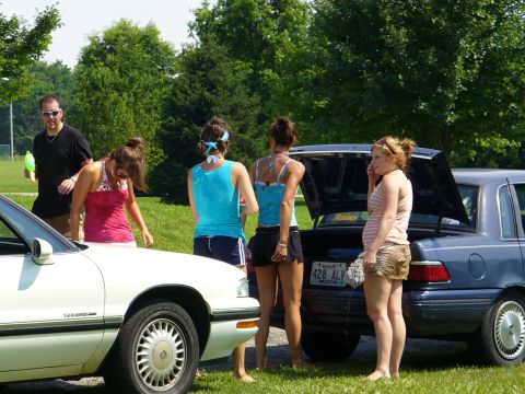 1991 Ford Probe - Several people stand around two cars, one white and one blue, with the blue car's trunk open.