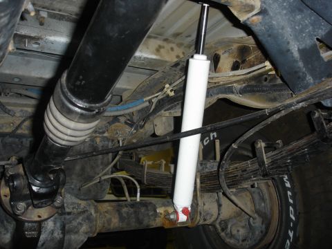 1996 Ford Bronco - Close-up of the rear suspension and drivetrain components of a vehicle, showing the driveshaft and leaf springs.