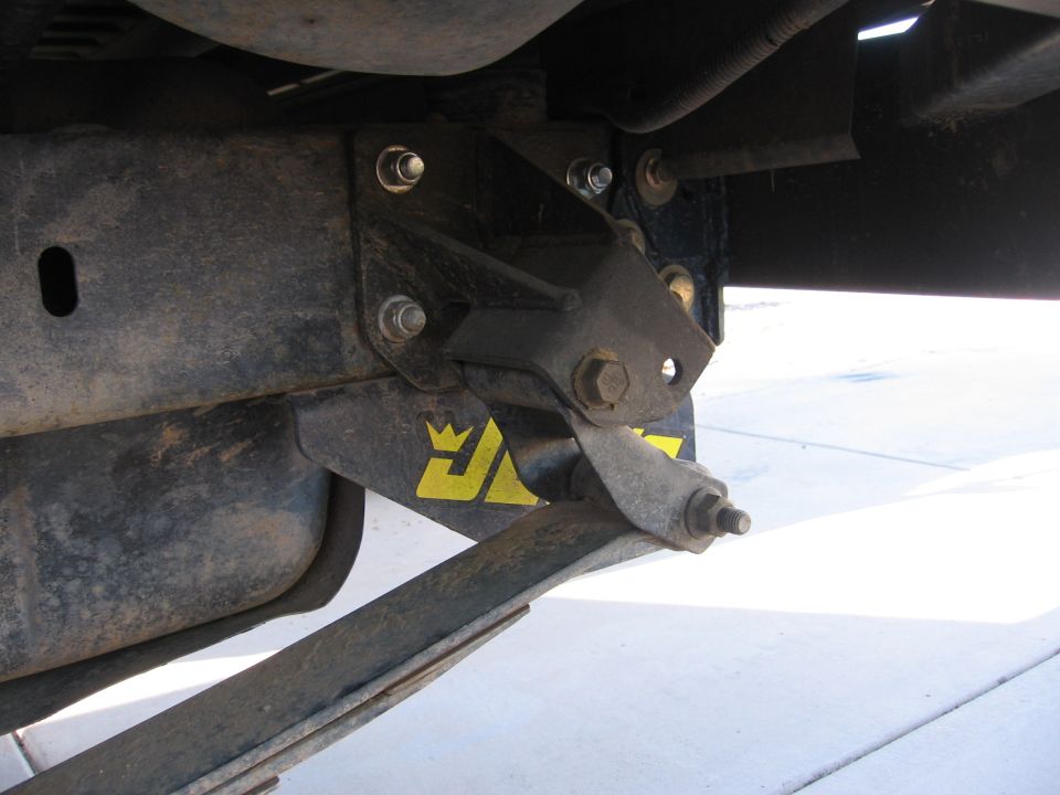 Yellow logo with crown on black suspension mount near leaf spring