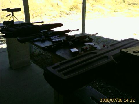 1990 Ford Bronco - Multiple firearms and ammunition are prepared on a table at an outdoor shooting range.