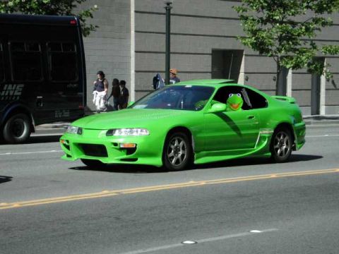 1977 Ford Mustang II - A bright green coupe is parked on the street, with a Kermit the Frog plush toy visible in the driver's side window.