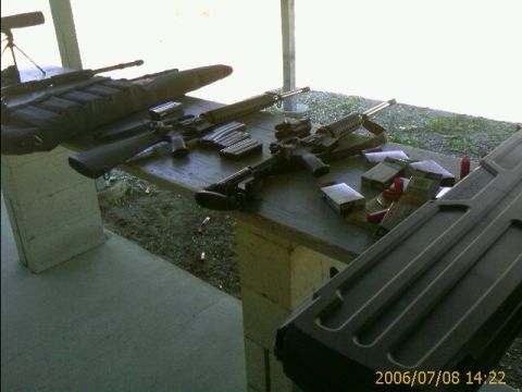 1990 Ford Bronco - A table at a shooting range is covered with firearms, ammunition, and magazines.
