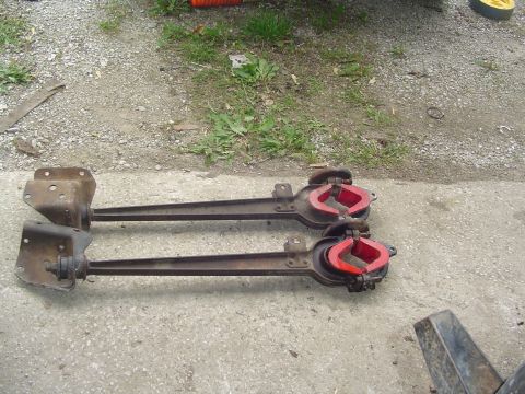 1990 Ford Bronco - Two axle housing components with red inserts are laid out on a gravel and concrete surface.
