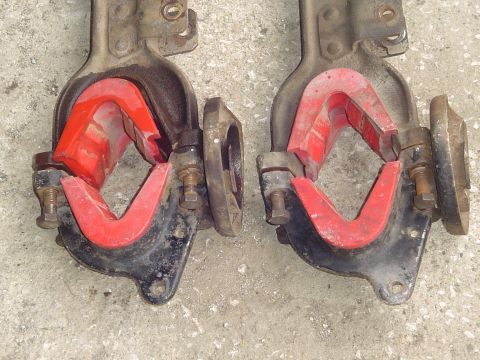 1990 Ford Bronco - Two automotive suspension parts with red rubber bushings are shown close-up against a concrete surface.