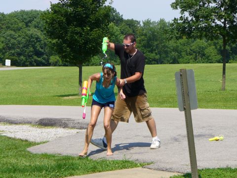 1991 Ford Probe - A man sprays a woman with a water gun in a park setting.