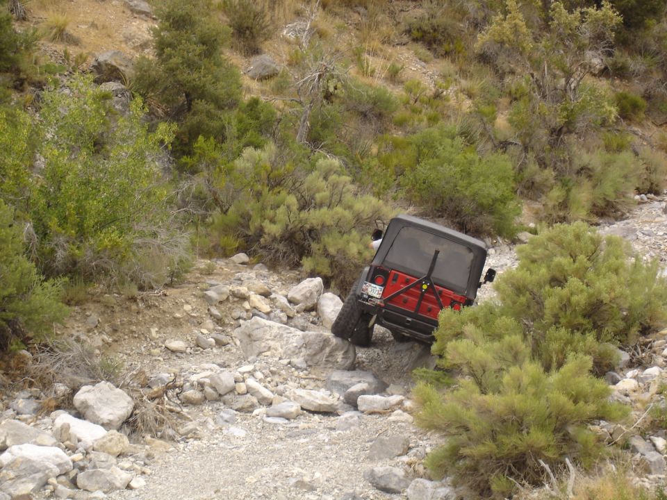 red Jeep Wrangler going over rocks on a trail