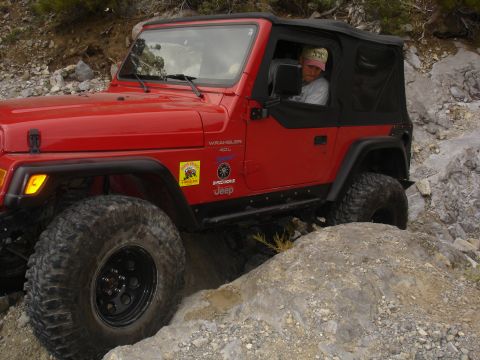 1996 Ford Bronco - A red Jeep Wrangler navigates a challenging rocky path.